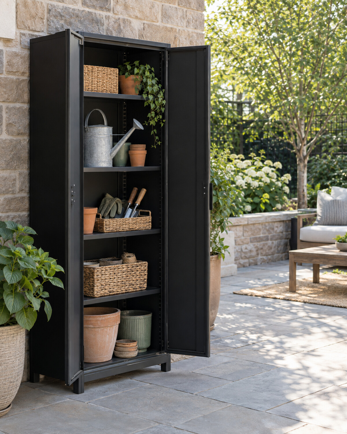 Narrow matte-black outdoor cabinet on a compact patio with doors open to organized shelves
