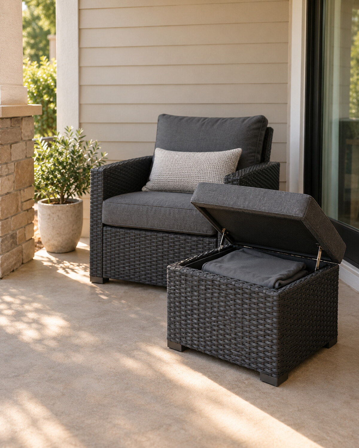 Compact charcoal outdoor storage ottoman beside a lounge chair with the lid partly open