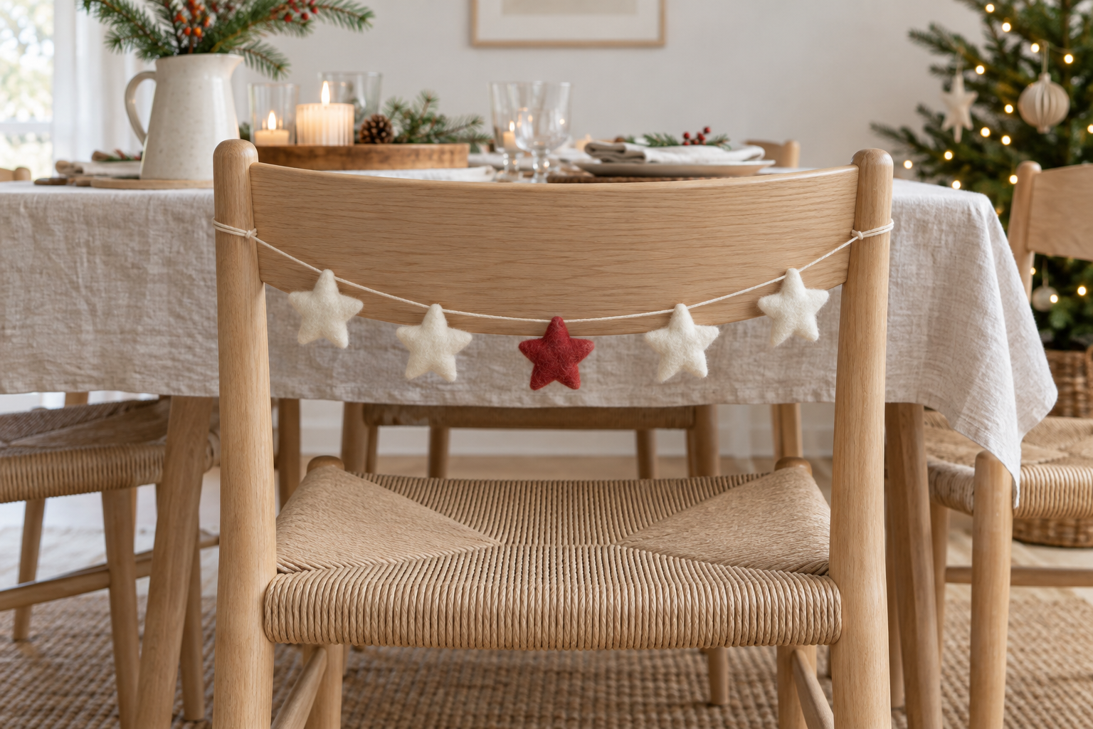 Four ivory felt stars and one red star strung across the outside of a light wood dining chair.
